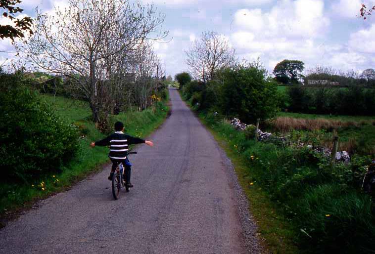 A boy riding a bicycle down a lane.